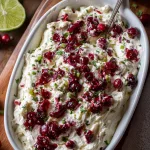 chunky cranberry jalapeño salsa over fluffy whipped cream cheese in a white serving dish